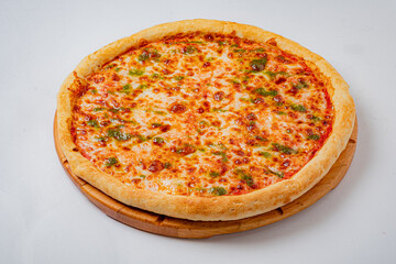 A golden pizza with melted cheese and green peppers rests on a wooden board