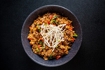 Enjoy a vibrant stir-fried rice bowl with colorful veggies, tender beef, and fresh sprouts