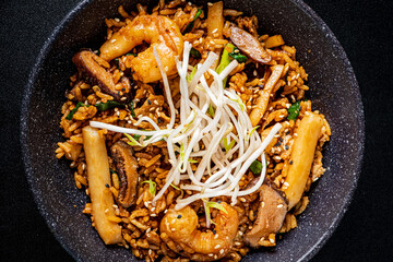 A vibrant dish of shrimp fried rice with vegetables, topped with fresh sprouts awaits your taste