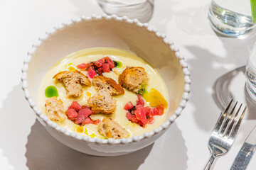 A rich, creamy soup with vibrant toppings awaits at a chic restaurant table