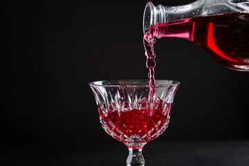 8K macro shot of red wine being poured into crystal glass, dark background, dramatic lighting