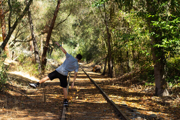 Balancing Act on Old Railway Tracks Surrounded by Autumn Leaves in a Serene Forest Setting
