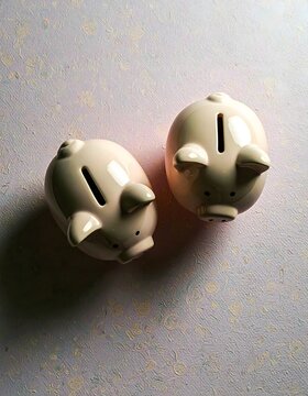 Dos huchas en forma de cerdito sobre fondo claro, s&iacute;mbolo de ahorro, econom&iacute;a familiar y planificaci&oacute;n financiera