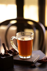Clear glass mug with hot black tea , with subtle steam rising from the surface at sunlit interior, a sense of warmth and autumn atmosphere