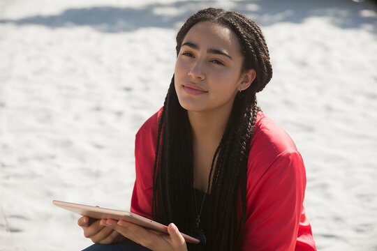 Young woman with dreadlocks holding a tablet outdoors