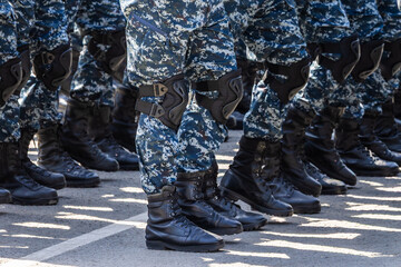 Multiple legs in urban camouflage gear standing in formation outdoors