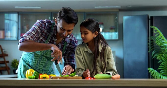 Indian father and daughter Chopping capsicum together, bonding in modern kitchen, Asian dad teaching young girl cooking, family quality time at home, child helping parent with meal preparation