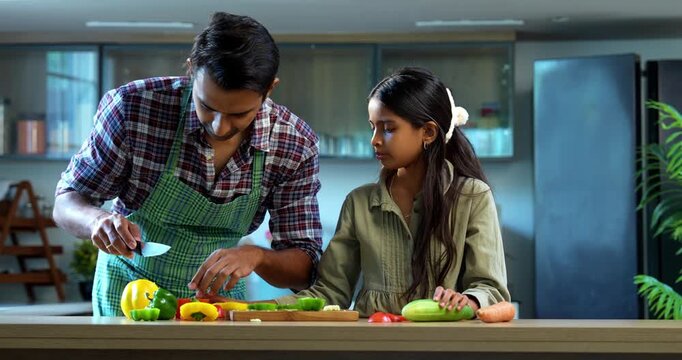 Indian father and daughter Chopping capsicum together, bonding in modern kitchen, Asian dad teaching young girl cooking, family quality time at home, child helping parent with meal preparation