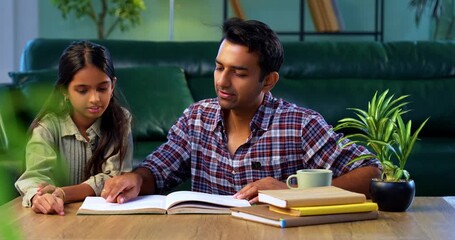 Teaching daughter from a text book, Indian young father helping child study while sitting together at table in modern home, Asian dad guiding girl with homework, family bonding and education - Powered by Adobe
