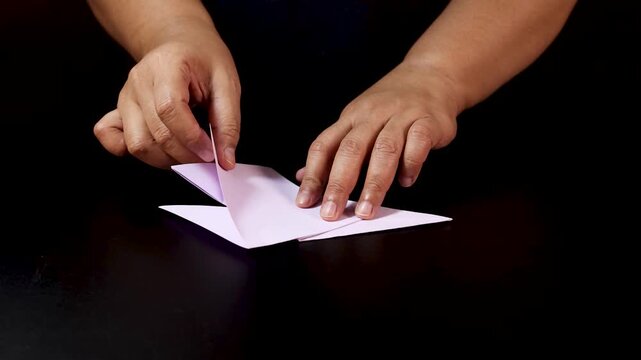 Hands Folding Pink Paper for Origami Craft Preparation
