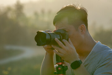 A male traveler photographs a breathtaking natural landscape during the golden hour of evening.