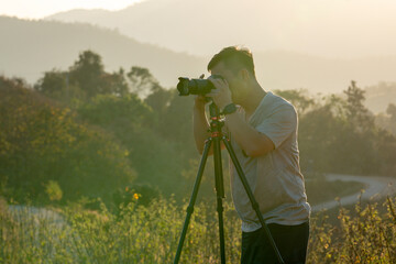A male traveler photographs a breathtaking natural landscape during the golden hour of evening.