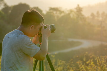 A male traveler photographs a breathtaking natural landscape during the golden hour of evening.