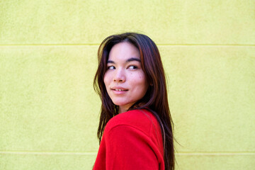 Young Asian woman with natural skin and charming acne, looking back playfully. Expressing authenticity and youthful style