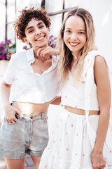 Two young beautiful smiling hipster female in trendy summer white t-shirt and shorts clothes. Sexy...