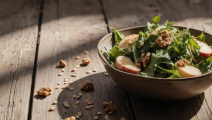 A fresh salad with apples and walnuts sits in a bowl on a rustic wooden surface, sunlit