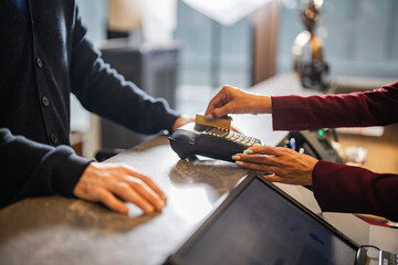 Focus Hotel receptionist hands processing guest payment with credit card at front desk. Concept of hospitality, travel, and cashless hotel check-in experience. Digital society and lifestyle concept.