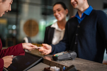 Hotel receptionist processing guest payment with credit card at front desk. Concept of hospitality,...