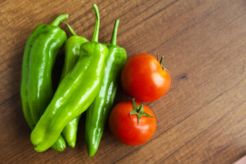 Fresh, tasty organic vegetables, red tomato and green pepper, isolated on brown wood cutting board