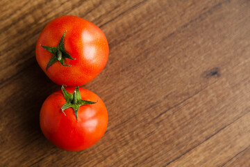 Fresh, tasty organic vegetables, two red tomato, isolated on brown wood cutting board