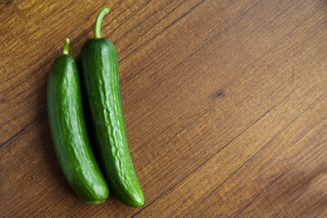 Fresh, tasty organic vegetables cucumber, isolated on brown wood cutting board