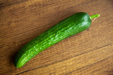 Fresh, tasty organic vegetables cucumber, isolated on brown wood cutting board