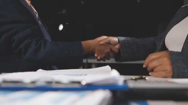 Business professionals shaking hands during a meeting with a laptop in the background symbolizing a successful partnership