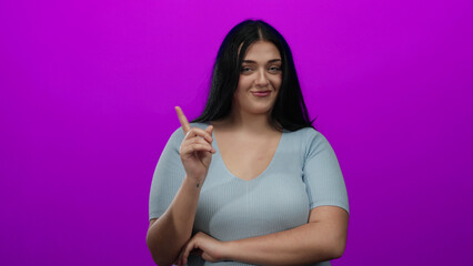 Obraz premium Young woman gestures no while pointing at herself against vibrant pink background expressing disagreement with confident smile.