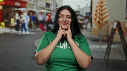 Curvy woman volunteer smiling in green shirt outdoors on busy city street in vibrant urban setting with lively people and cafes around