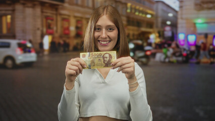 Young woman holds 5000 forint banknote on urban street at night, highlighting hungarian currency with vibrant outdoor city ambiance.