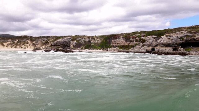 Drone dolly over ocean toward Klipgat Cave and Die Plaat coastline, De Kelders