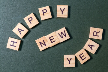 Wooden letter tiles spelling Happy New Year arranged neatly on a textured green background