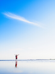 Woman standing joyfully in the serene sea under a bright sun in Sweden during a clear day