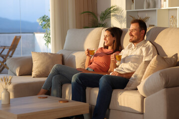 Obraz premium Happy couple drinking tea contemplating sunset on a couch