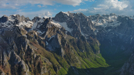 Fototapeta premium Rocky snow mountains before sunset aerial