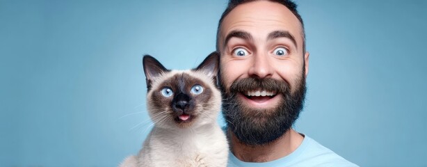 The joyful man with a cute Siamese cat against a blue background.