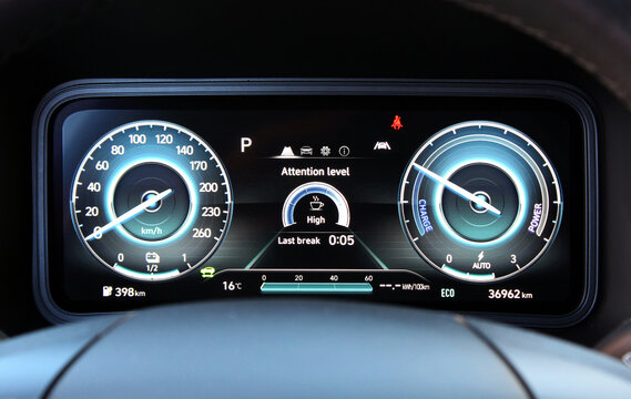 Modern digital instrument cluster in an electric vehicle with blue indicators for speed, charge, and power. Central display shows drivers attention level and selected Eco mode. Electric car dashboard.