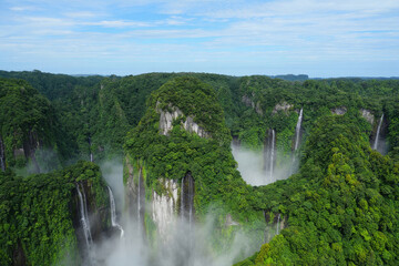 Majestic waterfalls cascade among green cliffs in an untouched tropical rainforest in the early morning light Generative AI