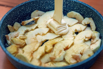 Sliced apples in a pan, covered with rich creamy custard, ready for baking a delicious dessert