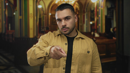 Man points finger towards a wooden pew beneath stained glass windows and arched ceiling in church...