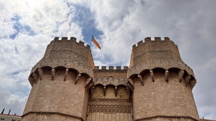 Quaint Fortress Towers: A medieval stone fortress stands under a cloudy sky, its towering structures displaying intricate architectural details. A historical building evokes a sense of time.