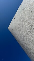 Skyward Gaze: An architectural marvel stands tall against a vast azure sky, its textured surface a testament to design and construction.