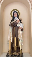 Serene Devotion: A captivating statue of a saint, radiating tranquility and reverence, is enshrined within an arched alcove, illuminating a sacred space with history and faith.