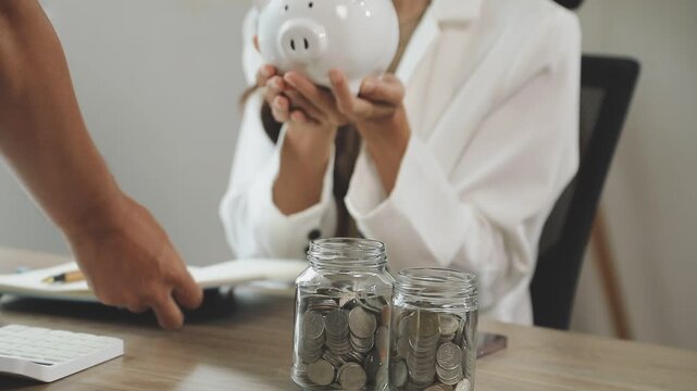 rAsian woman hand put coins in piggy bank,Saving money wealth and financial concept.