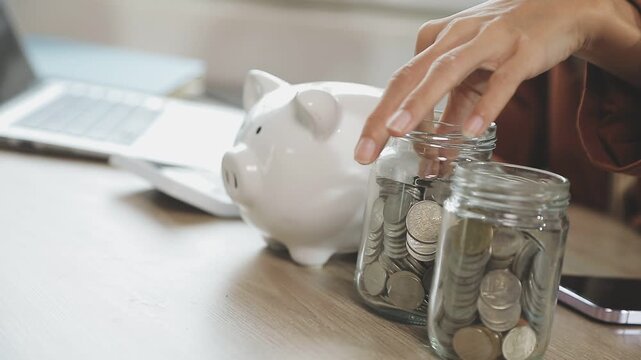 rAsian woman hand put coins in piggy bank,Saving money wealth and financial concept.