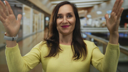 Hispanic woman holds hands apart to show large size gesture in brightly lit mall; scale display...