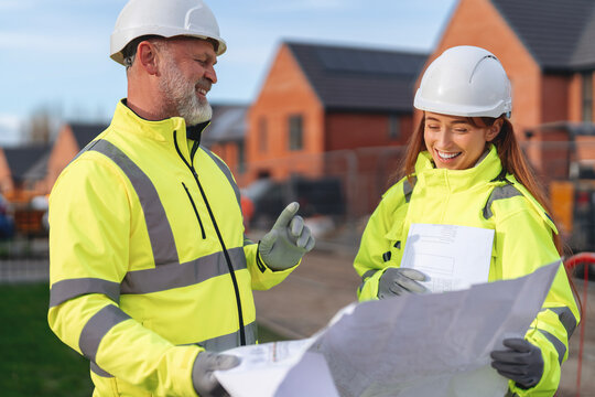 Construction team reviews blueprints in residential development site  for new housing project