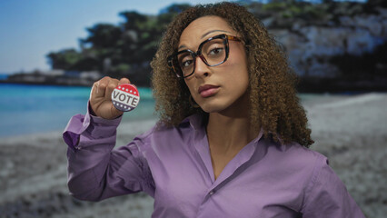 Hispanic transgender woman holding vote button and proudly pointing finger at button in studio;...
