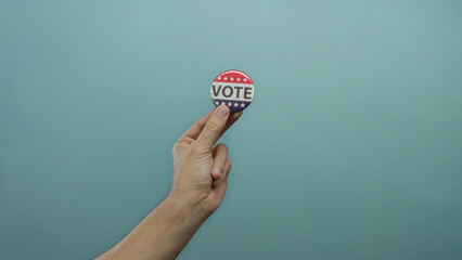 Hand holding vote button on blue background, showing political engagement and democracy,...