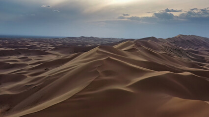 Aerial view of sand dunes in desert at sunset